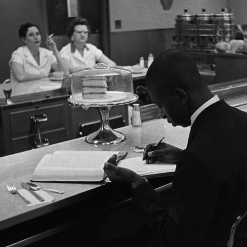 Black students from Saint Augustine College study while participating in a sit-in at a whites-only lunch counter in Raleigh, N.C. Two waitresses pointedly ignore them from the other side of the counter.