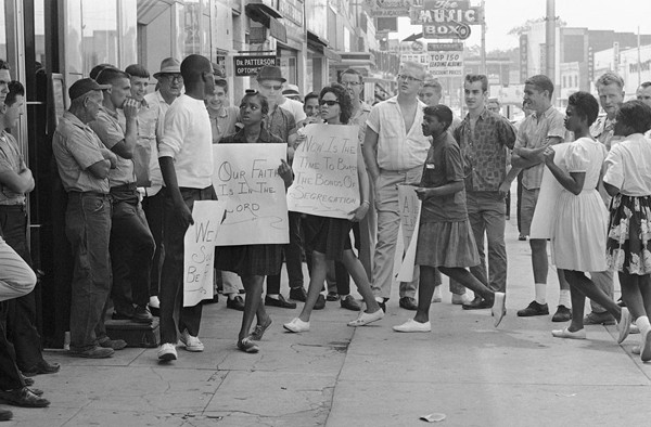 A picketer in front of a Gadsden, Alabama, drugstore turns to answer a heckler during a demonstration, on June 10, 1963. About two dozen black youths picketed several stores and two theaters.