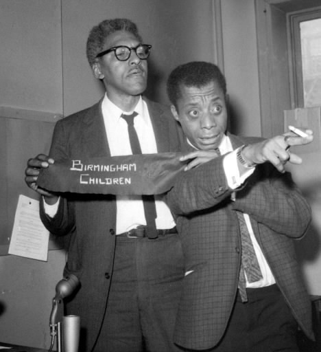 James Baldwin, right, author, and Bayard Rustin, Deputy Director of the March on Washington, comment upon Alabama incidents during a press conference in New York City on September 18, 1963. The two civil rights leaders called upon President John F. Kennedy to use troops to “break the hold” of Governor Wallace of Alabama, otherwise “there will be rioting in Alabama” which will affect the entire nation. They display arm bands to be worn at a rally scheduled in New York September 22 “to protest the brutal murder of Negro children in Birmingham.”
